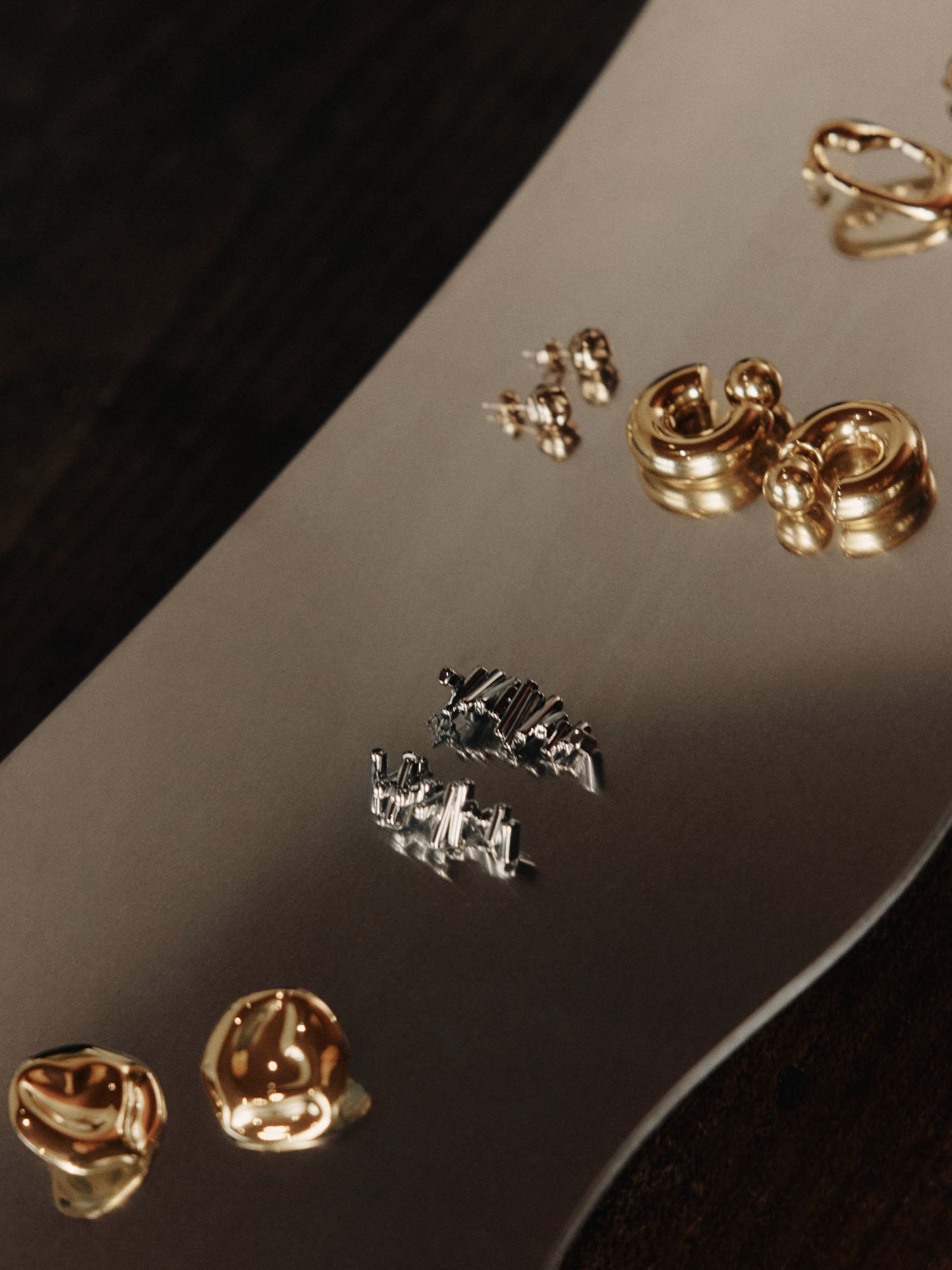 Goldene Ohrringe auf glänzendem Untergrund, elegant und modern – PURELEI.