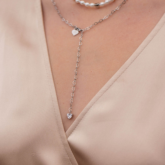 Silberne Herz-Kette von PURELEI, elegant und feminin, auf zartem Stoff getragen.