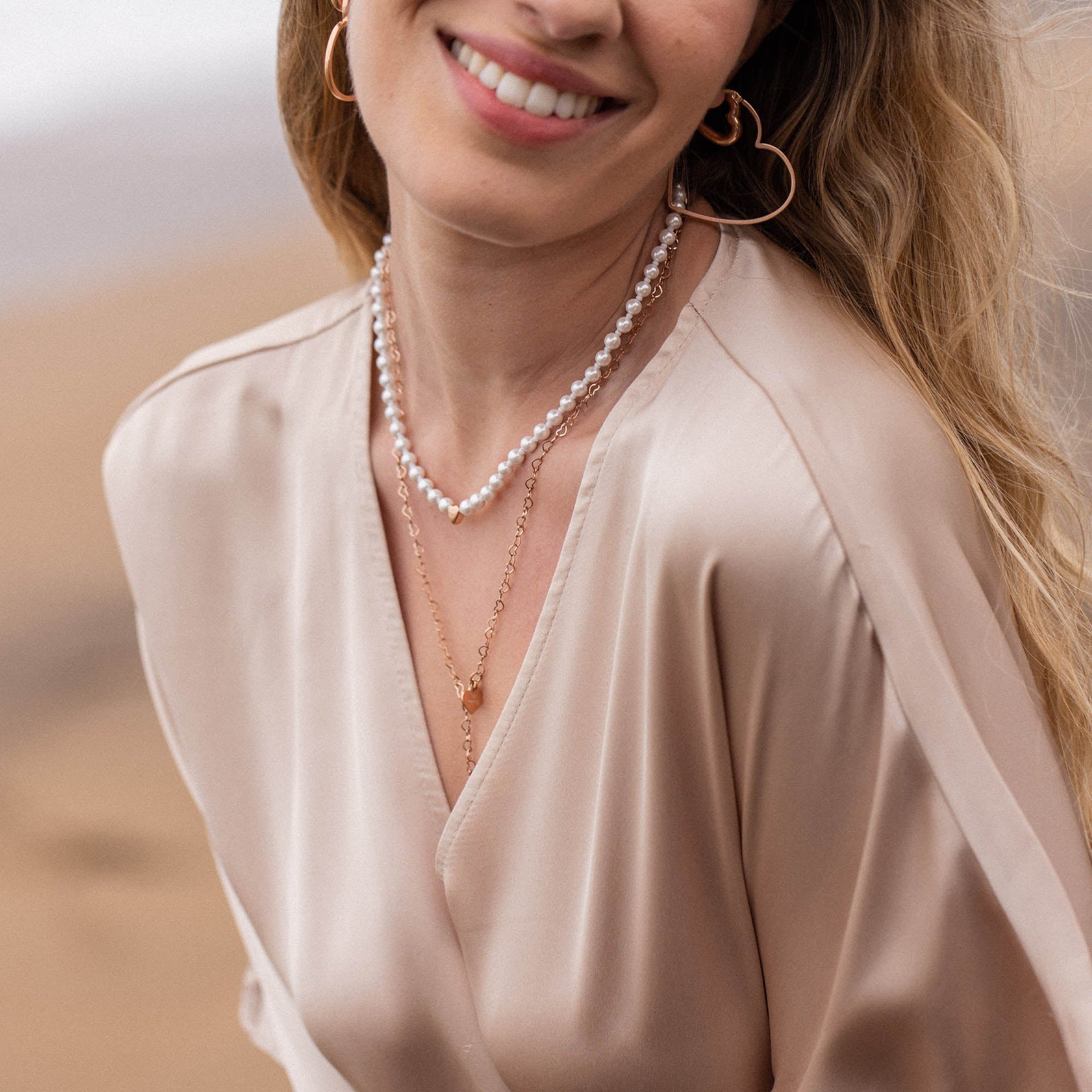 Perlenkette und goldene Anhänger von PURELEI, elegant und feminin, getragen mit sanftem Lächeln.
