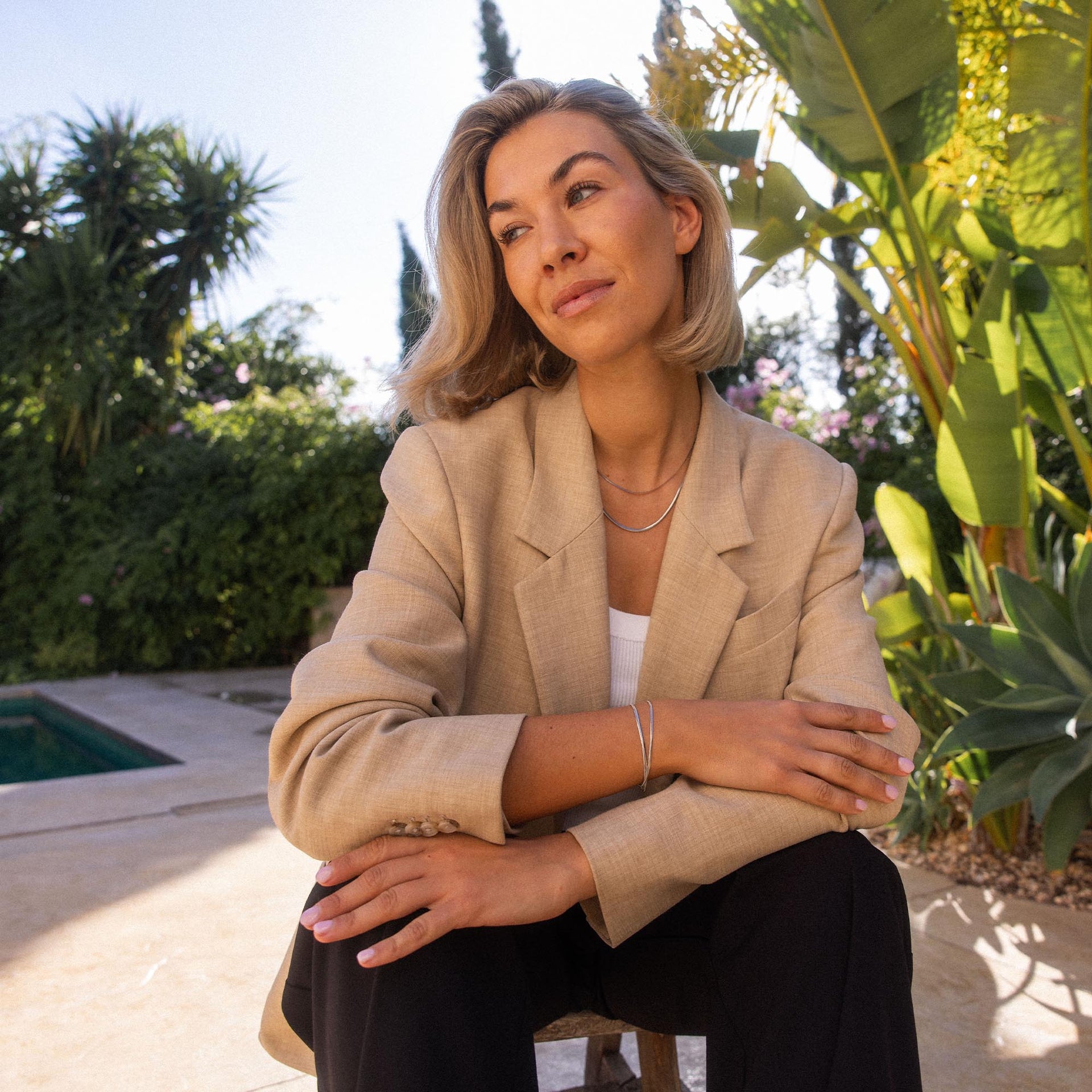 Elegante PURELEI Kette und Armband in einem tropischen Garten, warmes Licht und entspannte Stimmung.