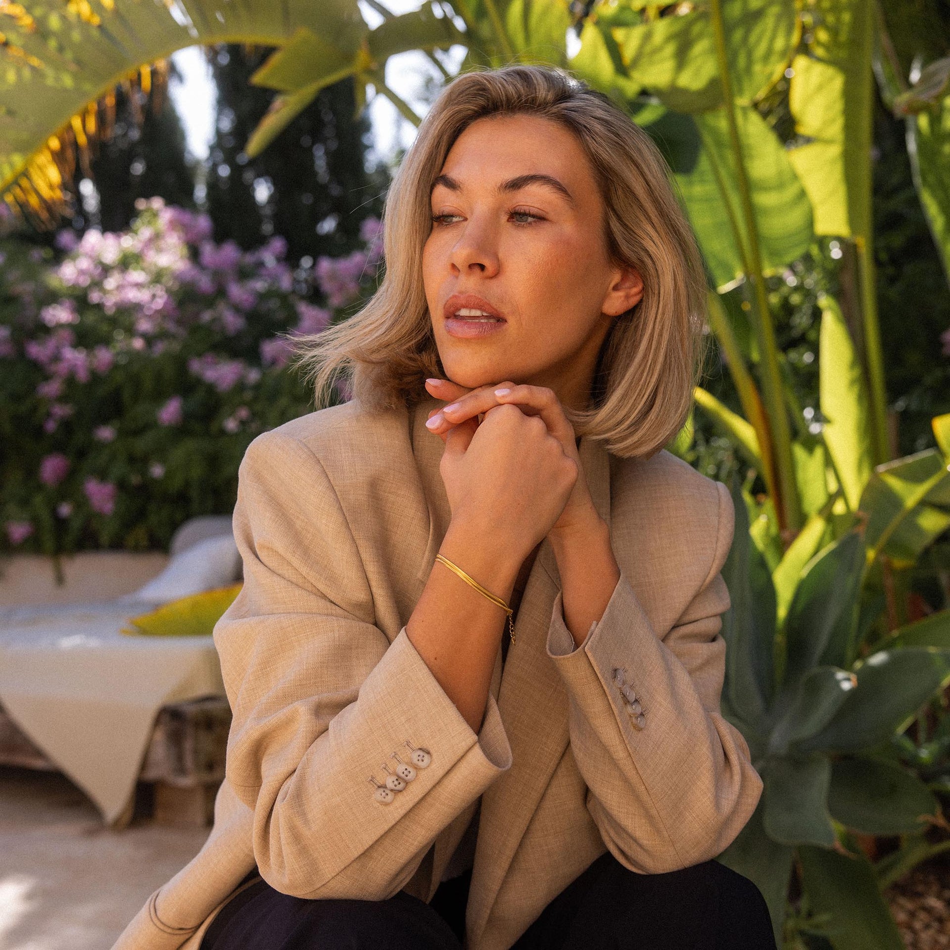 Elegantes, goldenes Armband von PURELEI, getragen in tropischer Umgebung.