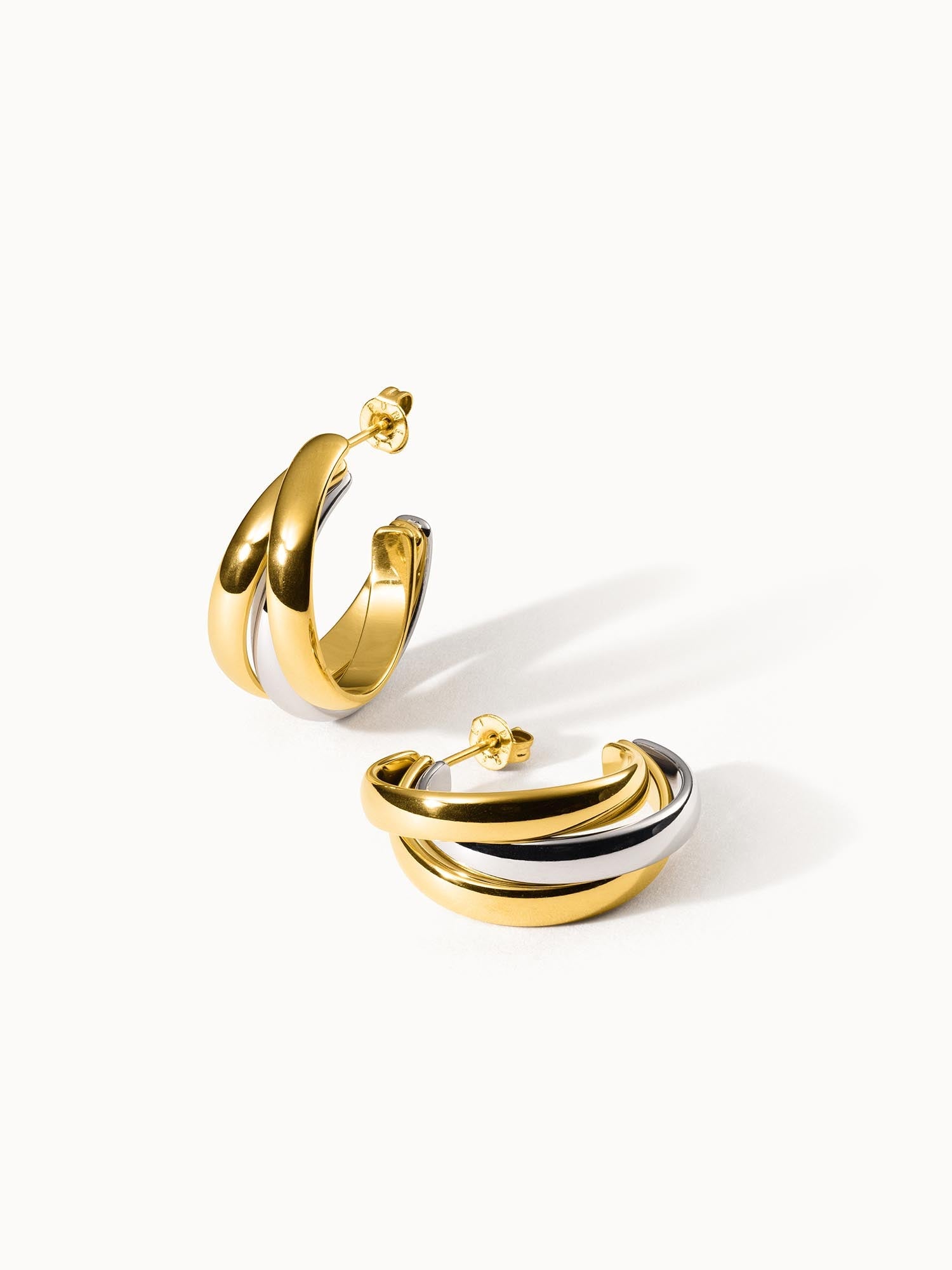 Goldene und silberne Creolen von PURELEI mit elegantem, geschwungenem Design.