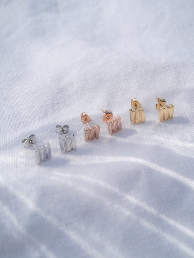 Serene Ohrringe von PURELEI in Silber, Roségold und 14K Gold, minimalistisch und elegant auf hellem Stoff arrangiert.