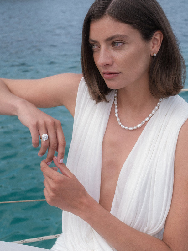 Allure Ring mit Stein, vergoldet, Muschel-Blütenmotiv mit weißem Zirkonia, getragen am Meer, PURELEI Stil