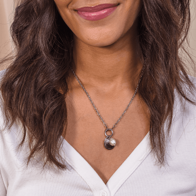 PURELEI Pearl Charm aus nickelfreiem Edelstahl mit Keshi-Perle, elegant getragen vor weißem Stoff, feminin und zeitlos.