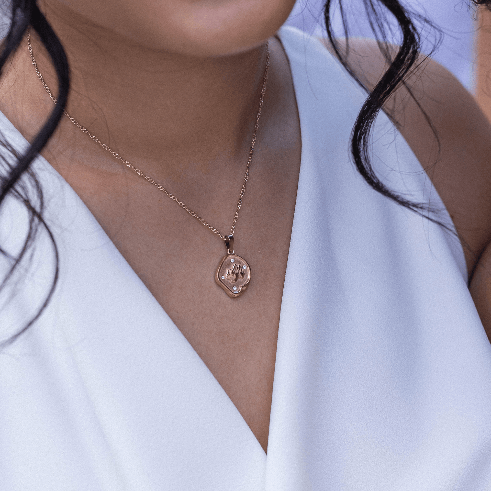 Roségoldene Kette mit einzigartigem Anhänger, getragen mit eleganter Bluse von PURELEI.