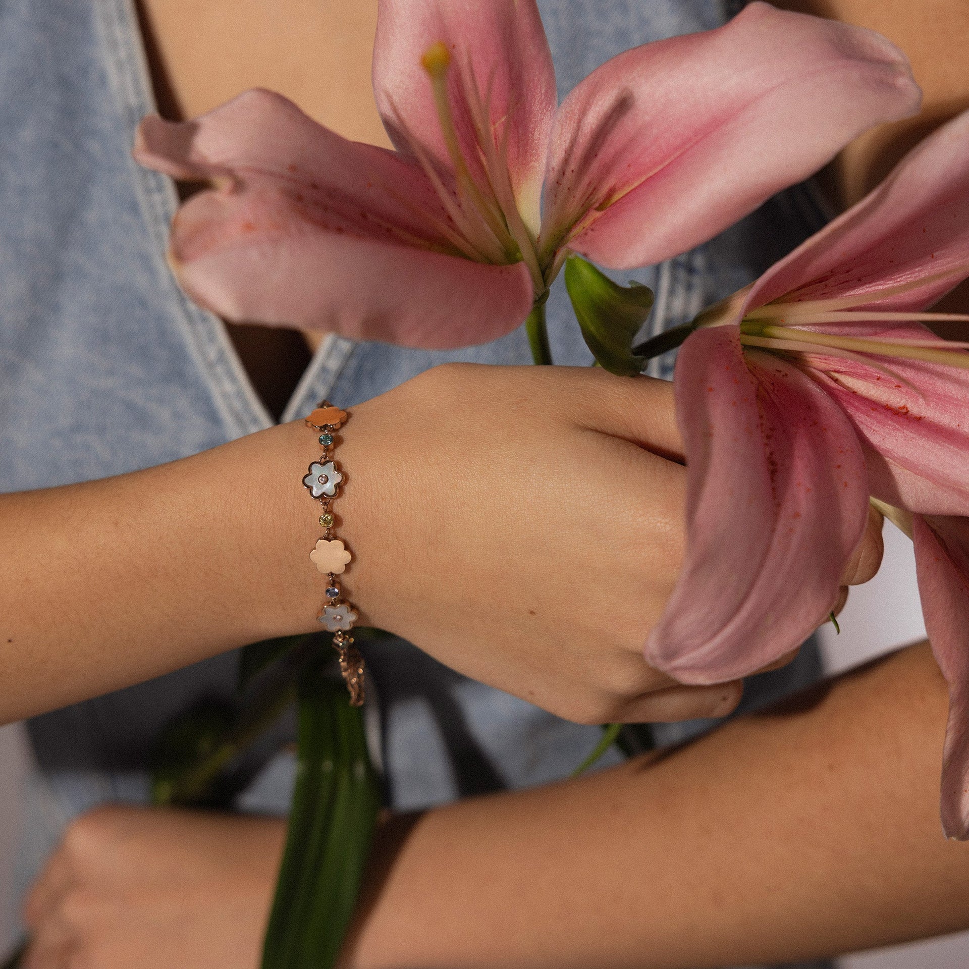 Roségoldenes Armband mit blühenden Anhängern, getragen mit Blumen von PURELEI.