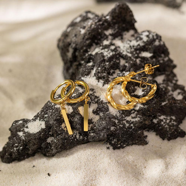 PURELEI Huli Creole Ohrringe aus 18K vergoldetem Edelstahl mit geometrischem Charm, elegant auf Lava-Sand.