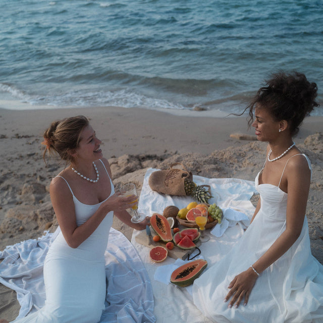 PURELEI Ocean Radiance Kette aus goldfarbenem Edelstahl mit Zirkonia und Muschel, elegant am Strand getragen.