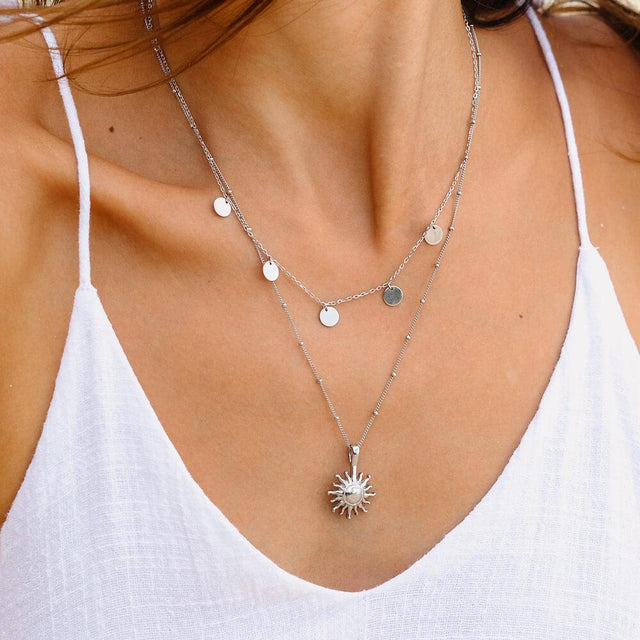 PURELEI Sun Kette in Silber mit filigranem Sonnenanhänger, getragen zu weißem Sommeroutfit, strahlt feminine Leichtigkeit.