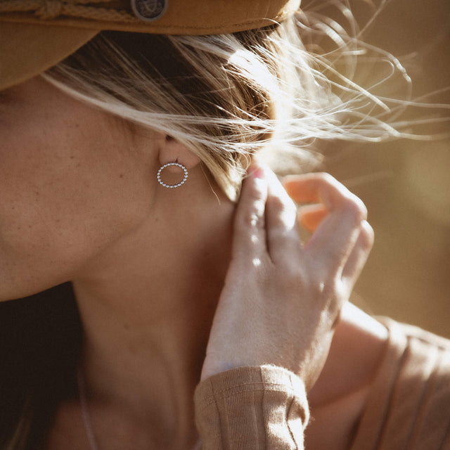 Karma Ohrringe aus silberfarbenem Edelstahl in Kreisform, elegant am Ohr getragen, PURELEI-Ästhetik, nickelfrei.