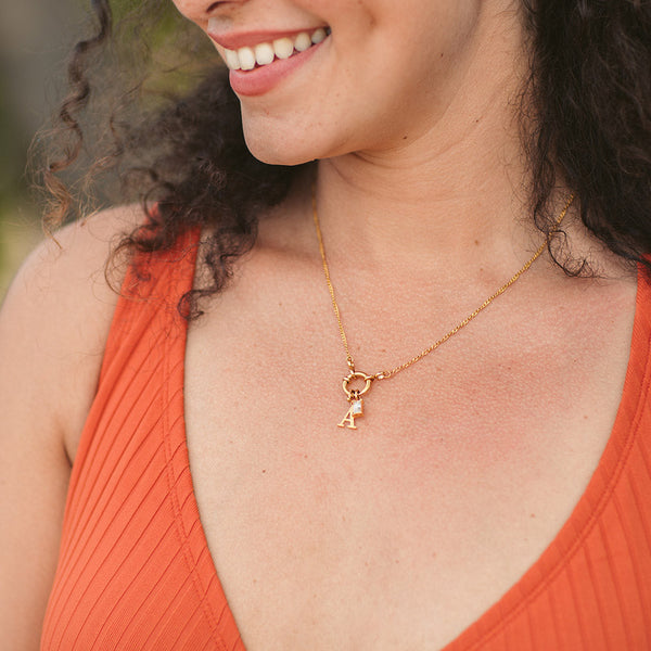 PURELEI Pure A Charm Buchstabenanhänger aus 18K Gold, elegant getragen, warm und feminin am Dekolleté.