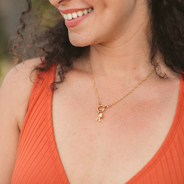 PURELEI Pure A Charm Buchstabenanhänger aus 18K Gold, elegant getragen, warm und feminin am Dekolleté.