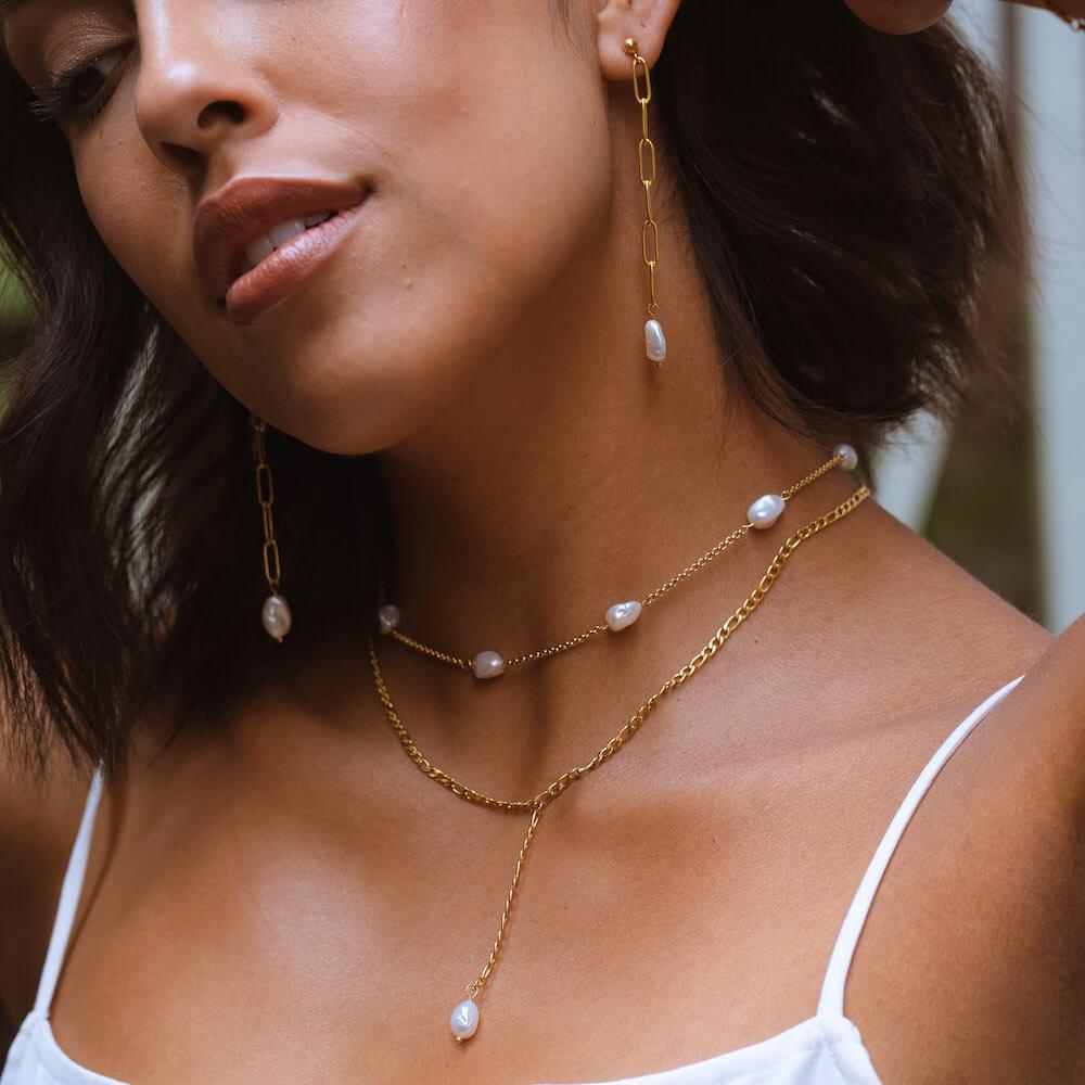 PURELEI Malahi Kette mit goldener Edelstahlkette und Süßwasserperlen, elegant getragen zu weißem Top.