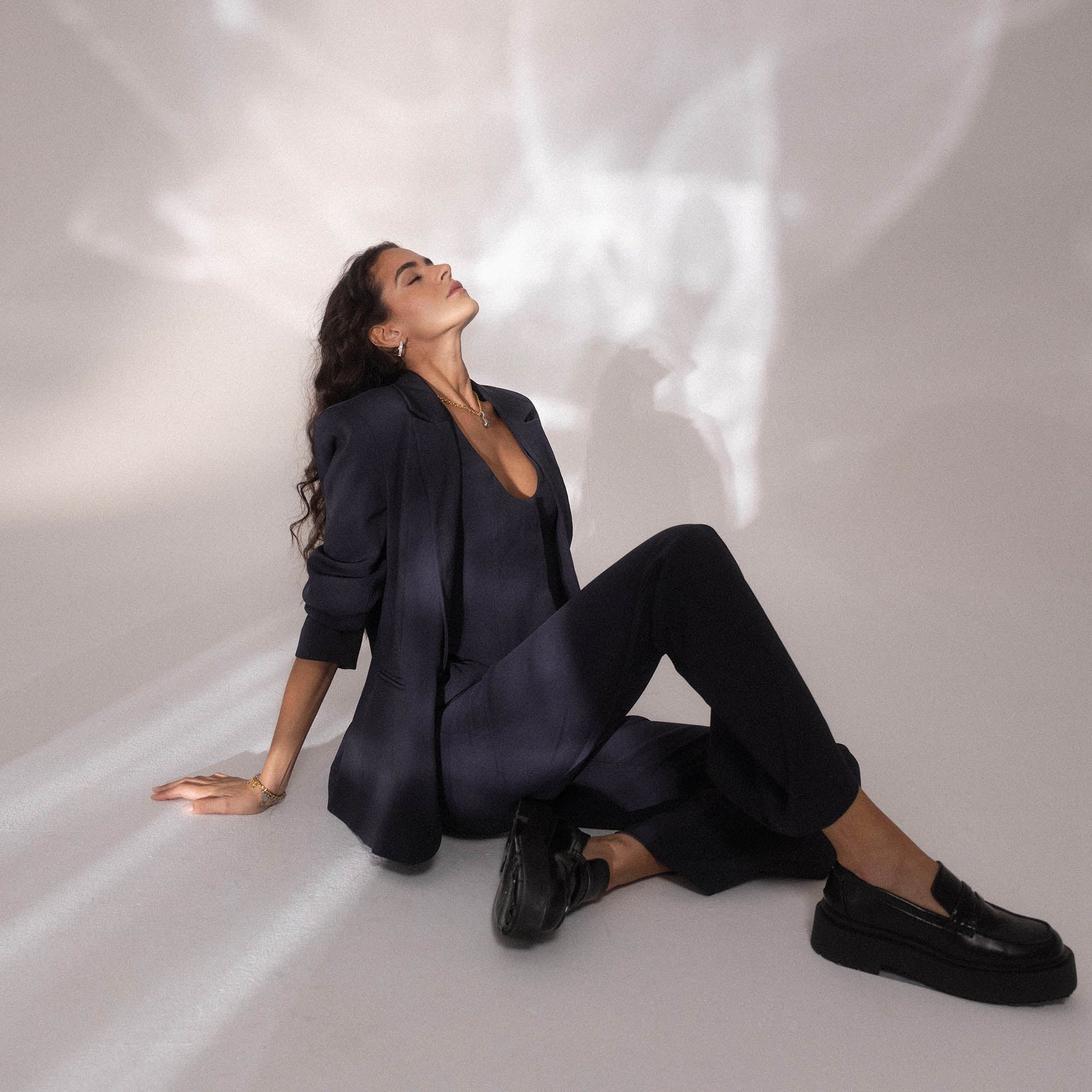 Elegante schwarze Kleidung, entspannte Pose, PURELEI inspiriert von urbaner Eleganz.