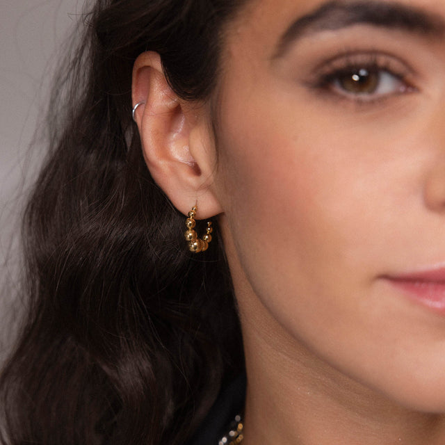 Roségoldene Creolen mit Kugeldesign, getragen von einer Frau, PURELEI.