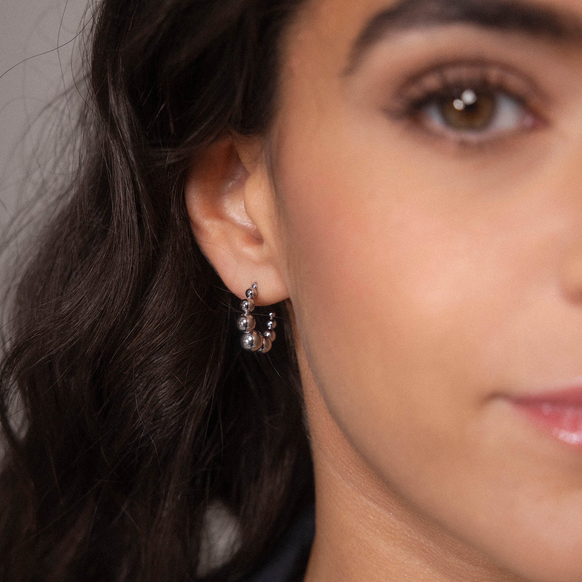 Silberne Ohrringe mit Kugeldesign, getragen von einer Frau, PURELEI inspiriert.