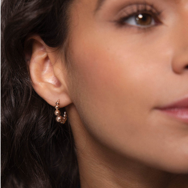 Roségoldene Creolen mit runden Details, getragen von einer Frau, PURELEI inspiriert.