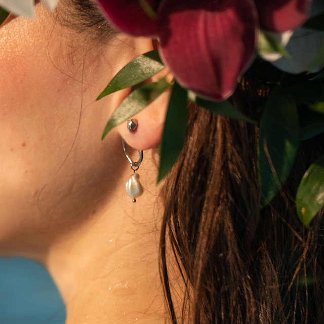 Elua Ohrringe mit silberner Öse und schimmernder Keshi-Perle, getragen im sanften Sonnenlicht von PURELEI