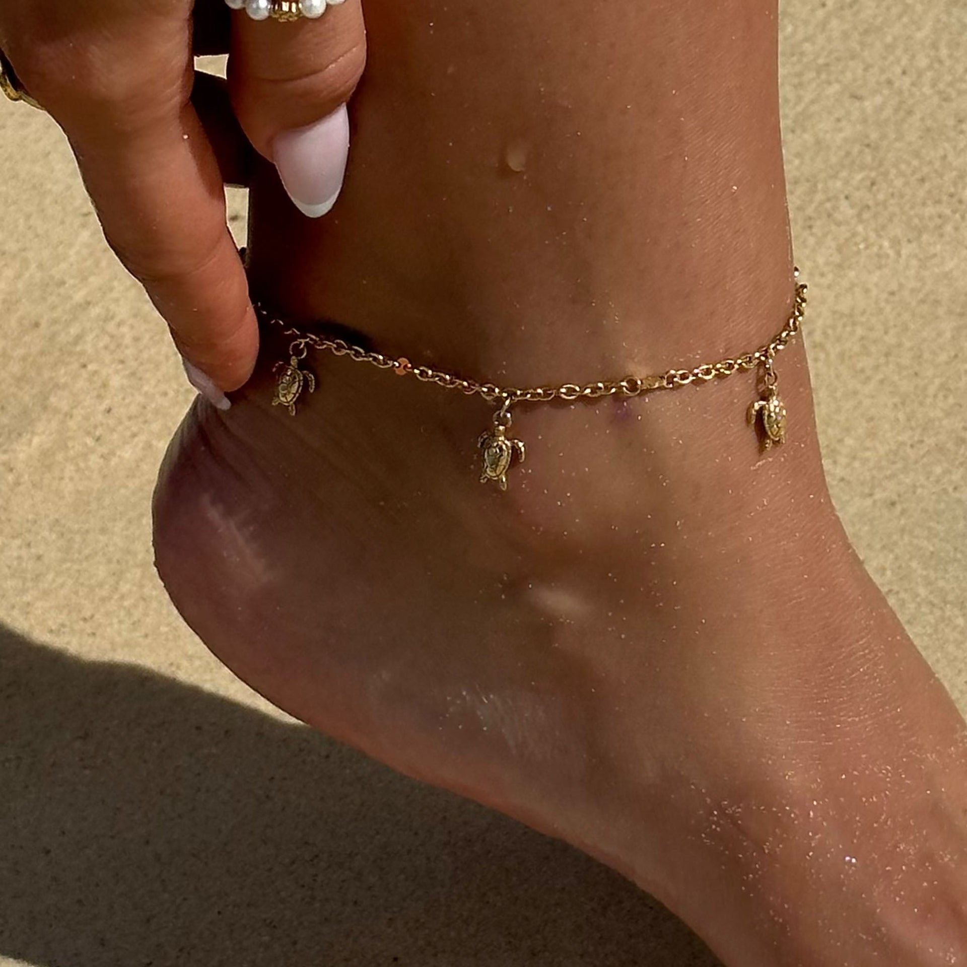 Goldenes Fußkettchen mit Schildkröten-Anhängern, getragen am Strand – PURELEI.