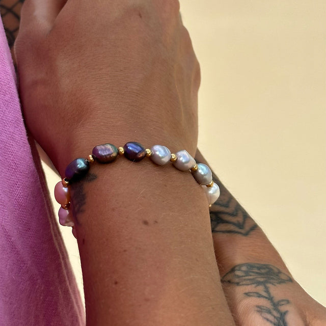 Perlenarmband mit lila und weißen Muscheln, getragen von PURELEI.