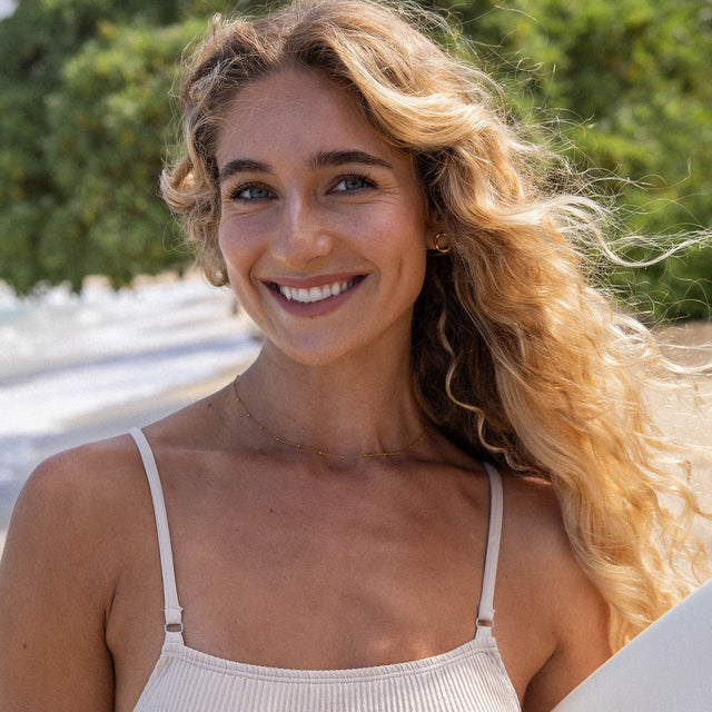 Feingliedrige Li’ili’i Kette aus 18K Gold vergoldetem Edelstahl, getragen am Strand, elegant und pur – PURELEI.