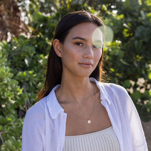 Goldene Sonnensonnenkette von PURELEI, getragen mit frischem, natürlichem Look im Freien.