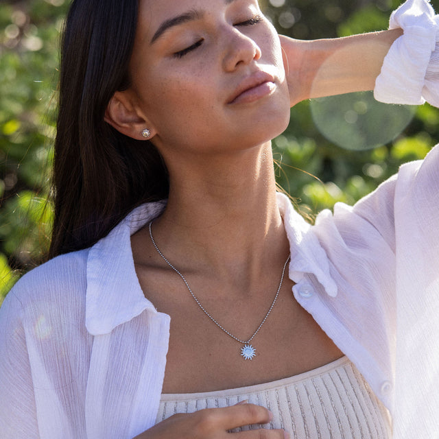 Silberne Kette mit Sonnenmotiv, getragen von einer Frau im Freien, PURELEI.