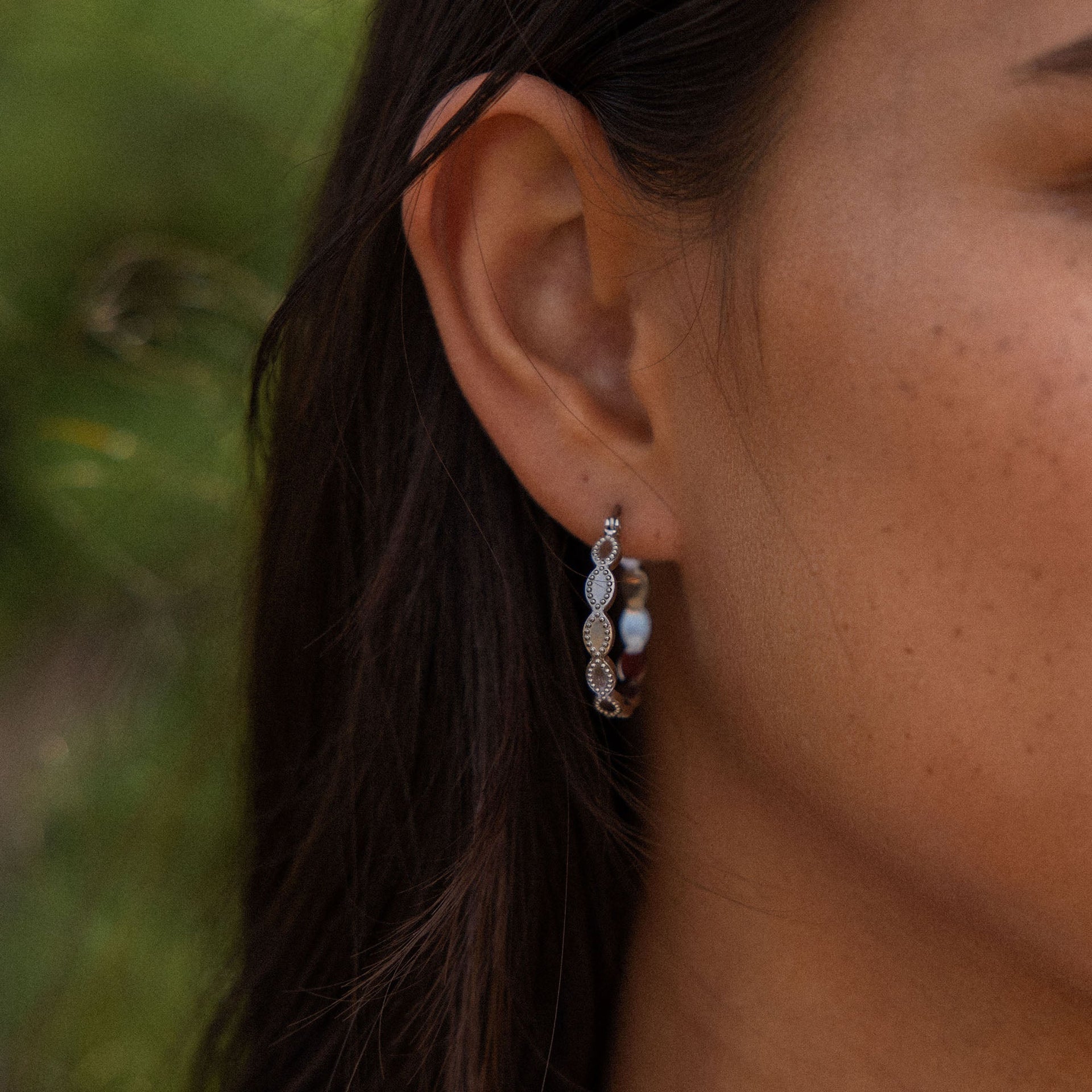 Elegante, silberne Creolen mit geschwungenem Design, getragen von PURELEI.