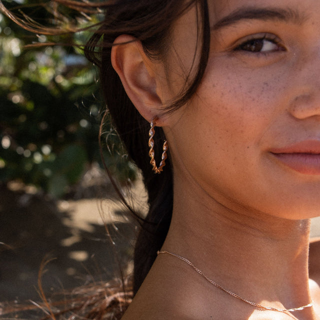 PURELEI Kaula Creole Ohrringe in Gold mit gedrehtem Design, getragen bei sanftem Tageslicht im natürlichen Setting