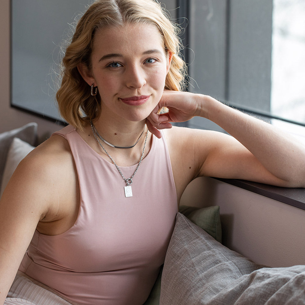 Hula Ohrringe aus vergoldetem Edelstahl, clean & elegant, getragen von Frau mit relaxed-emanzipierter Ausstrahlung in hellem Interieur