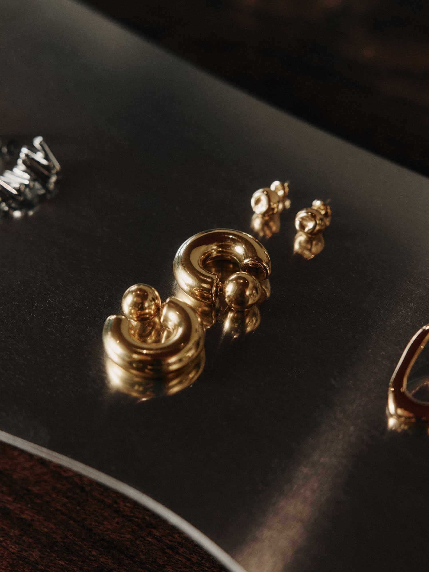 Goldene Ohrringe von PURELEI auf dunklem Untergrund, elegant und modern.