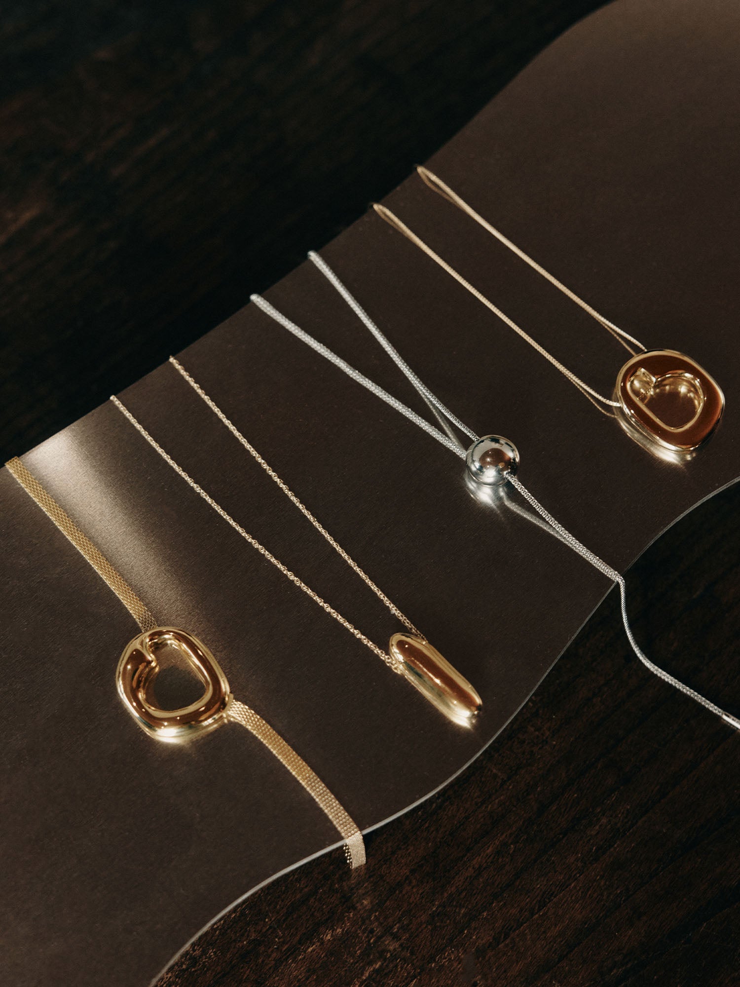 Silberne Ketten mit modernen Anhängern auf dunklem Hintergrund von PURELEI.