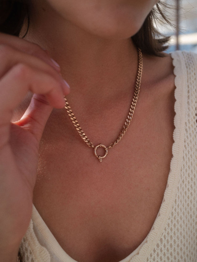 PURELEI Bold Charm Kette in Gold mit Charm-Verschluss, markant und feminin am Dekolleté getragen.