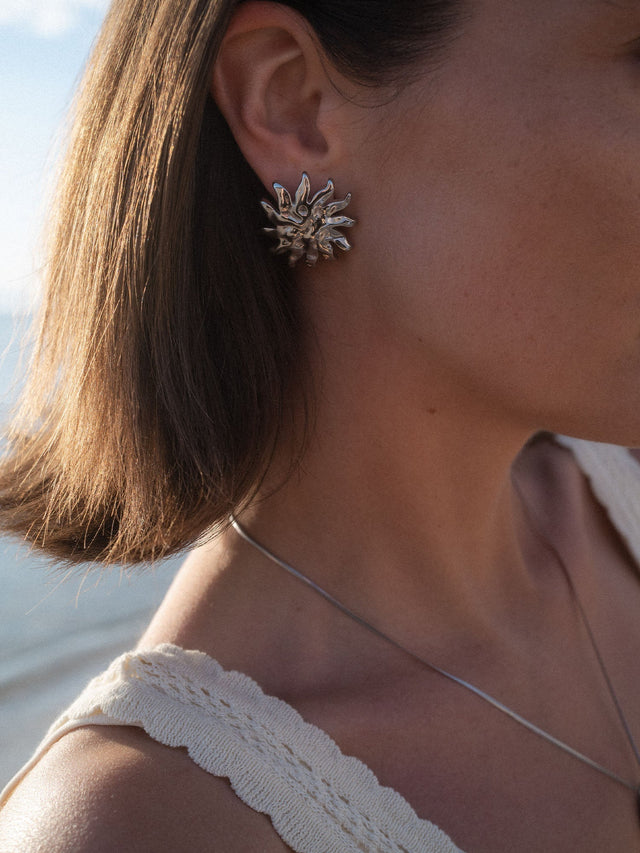 Silberne Iconic Sun Ohrringe mit strukturierter Oberfläche, getragen am Ohr in natürlichem Sonnenlicht, PURELEI.