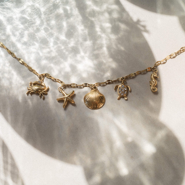 Silberne Kette mit maritimen Anhängern von PURELEI, umgeben von sanften Lichtreflexionen.