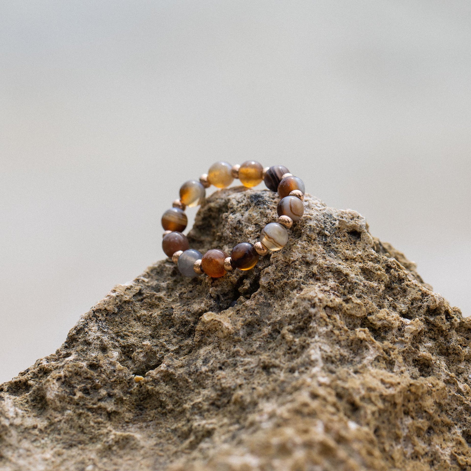 Anxiety Mahina Club Mokupuni Ring mit Natursteinperlen in warmen Erdtönen auf rauem Lavagestein, PURELEI.