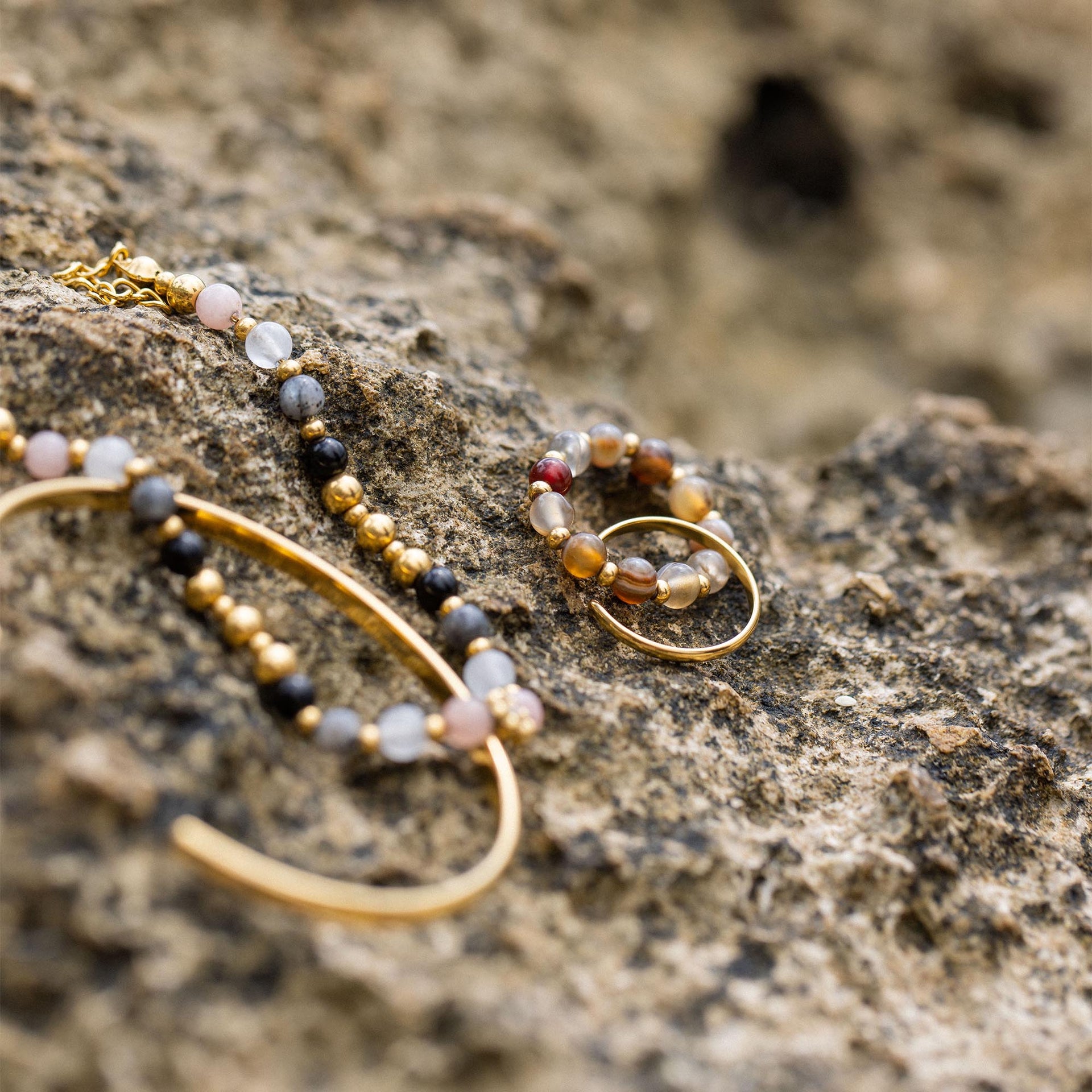 PURELEI Anxiety Mahina Club Mokupuni Ring mit Naturstein- und Edelstahlperlen auf rauem Strandgestein