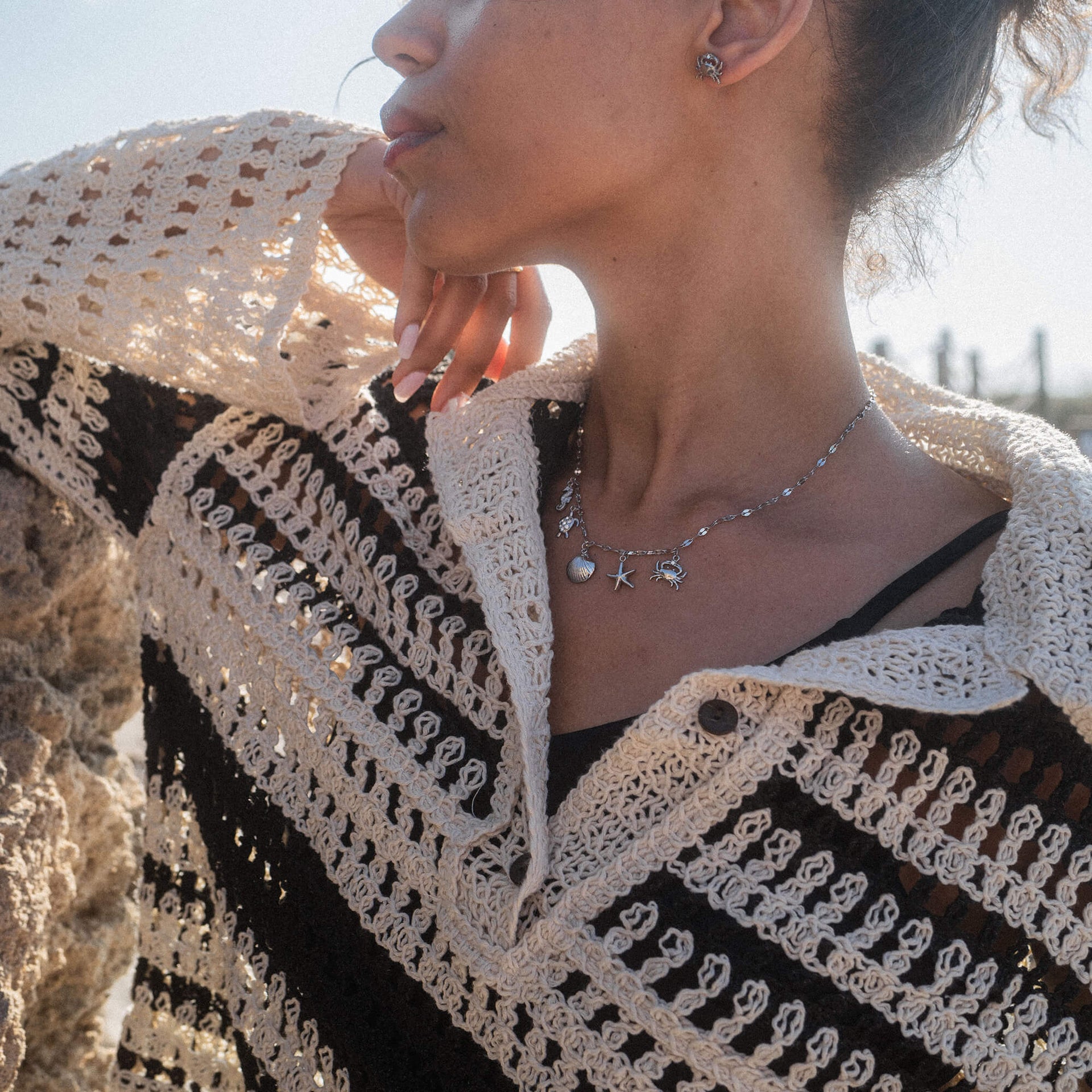 Silberne Kette mit maritimen Anhängern, getragen in sonniger Atmosphäre, PURELEI.
