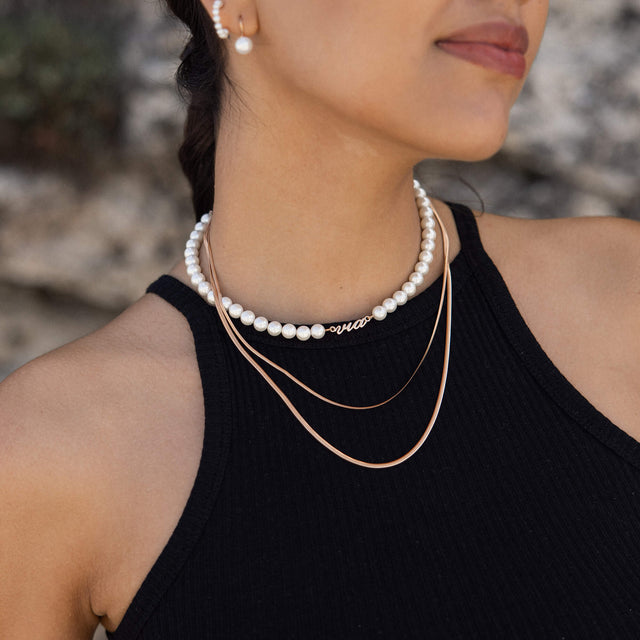 Drei elegante Ketten in Weiß und Gold von PURELEI, getragen mit femininer Ausstrahlung.