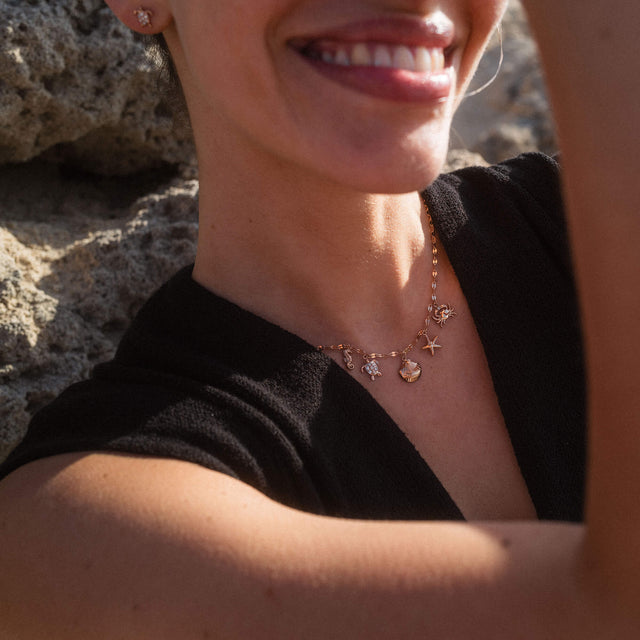 Roségoldene Kette mit maritimen Anhängern, getragen in sonniger Atmosphäre – PURELEI.