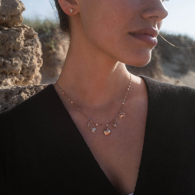 Goldene Kette mit maritimen Anhängern, getragen von einer Frau, PURELEI.