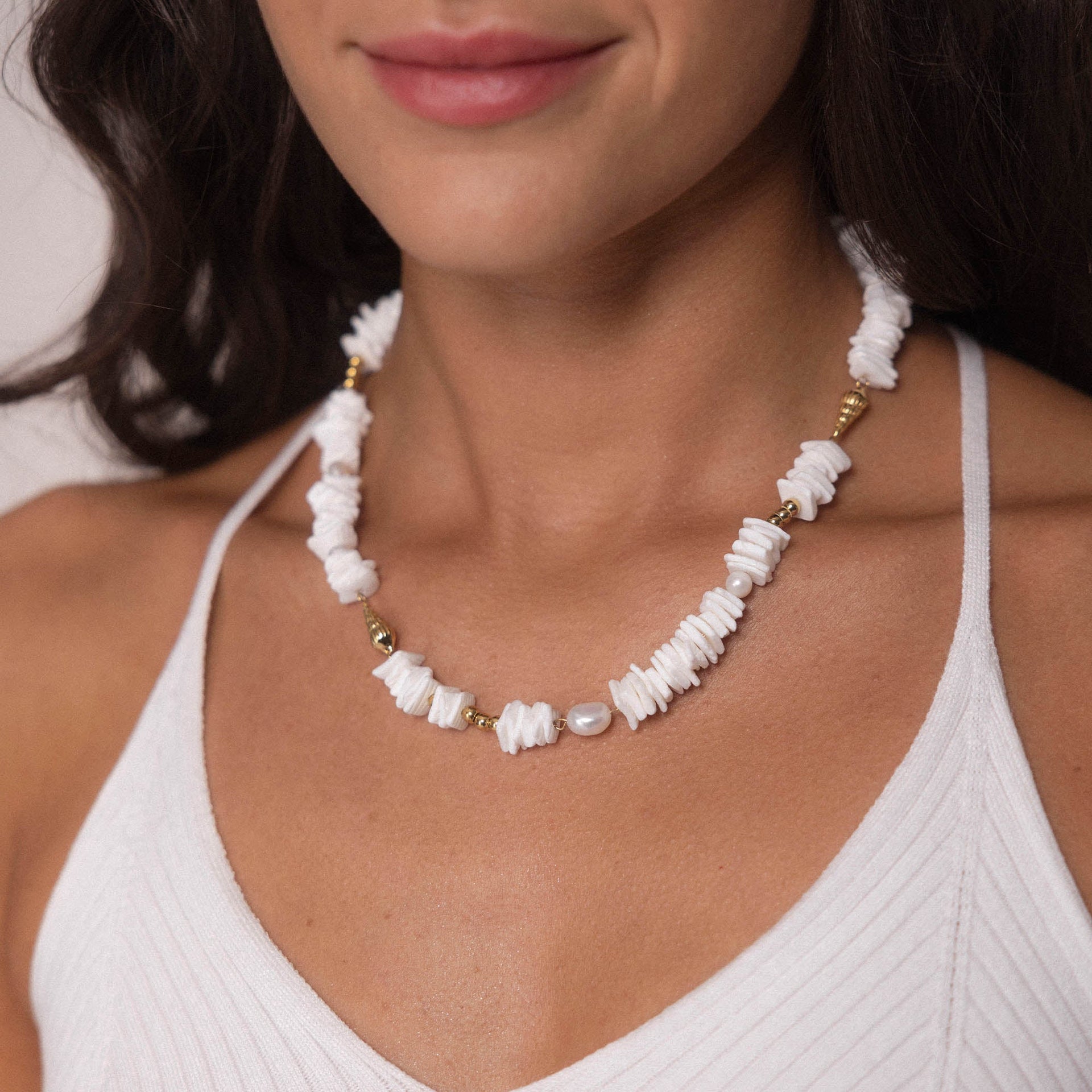 Wela Kette von PURELEI mit weißen Muschelstücken und Perle, goldenen Akzenten, marine-inspiriert und feminin getragen.