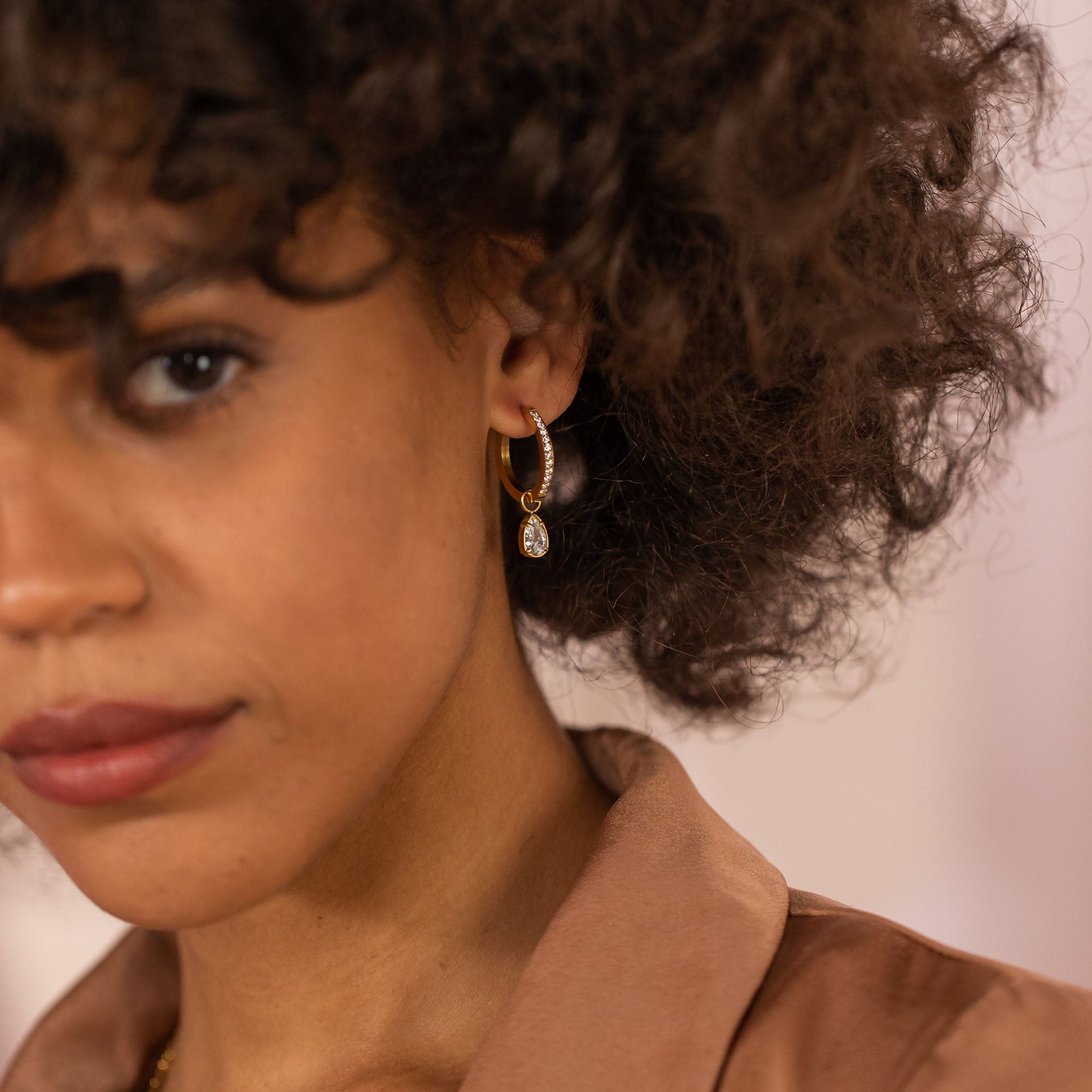 Roségoldene Creolen mit funkelndem Anhänger, getragen von einer Frau, PURELEI.