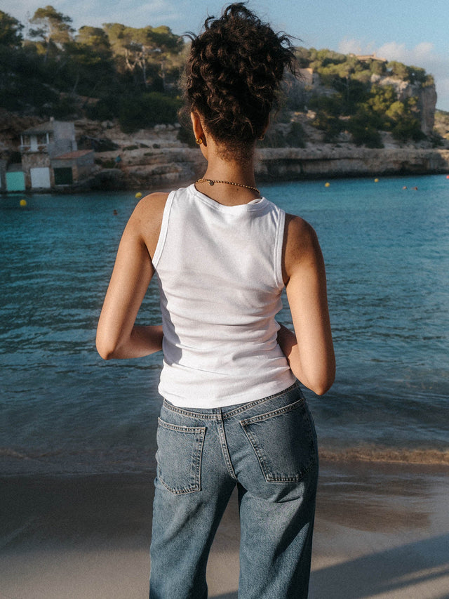 Weißes, geripptes PURELEI Simplicity Top aus Baumwolle, schlicht und elegant am Strand getragen.