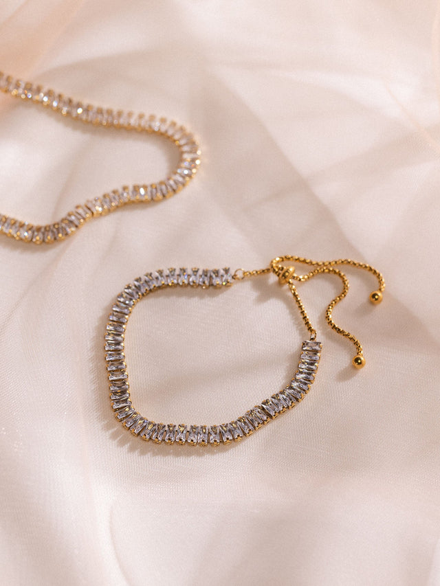 Goldene Kette mit funkelnden Steinen auf zartem Stoff, PURELEI Eleganz.