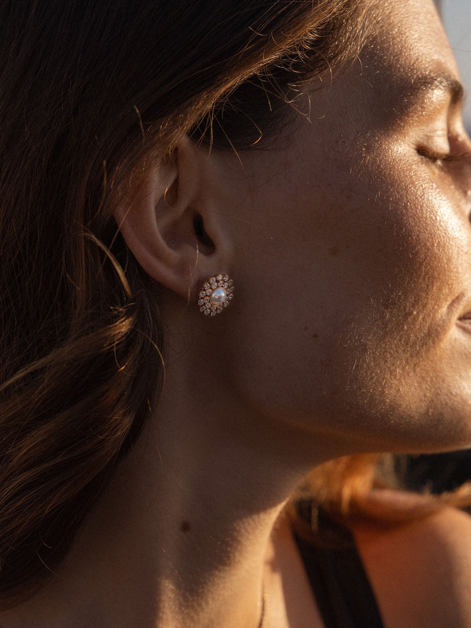 Goldene Ohrringe mit funkelndem Design, getragen von einer Frau im Sonnenlicht – PURELEI.