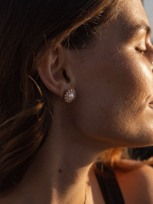 Goldene Ohrringe mit funkelndem Design, getragen von einer Frau im Sonnenlicht – PURELEI.