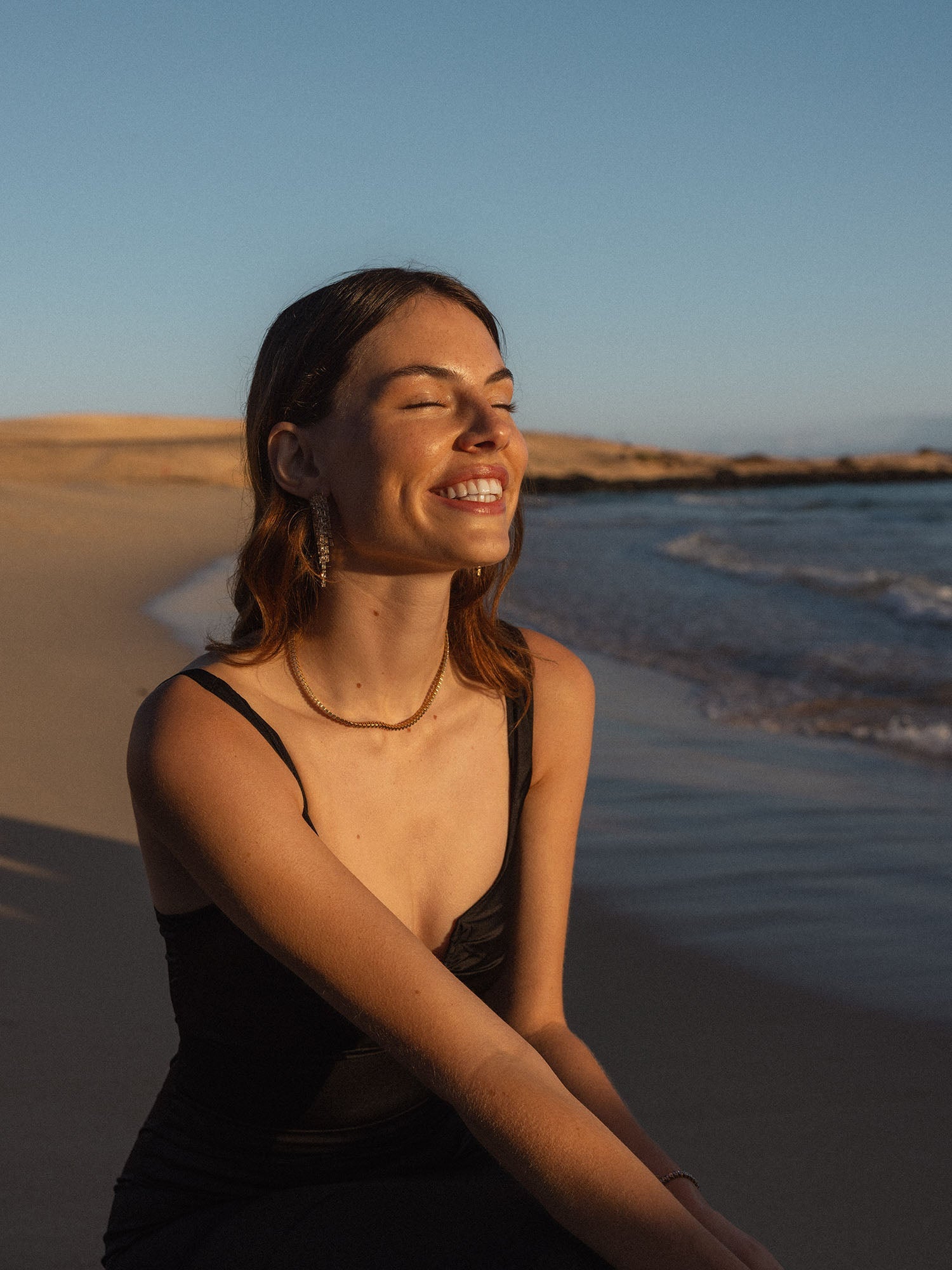 PURELEI Kette aus feinem Material, getragen am Strand, in warmem Sonnenlicht.