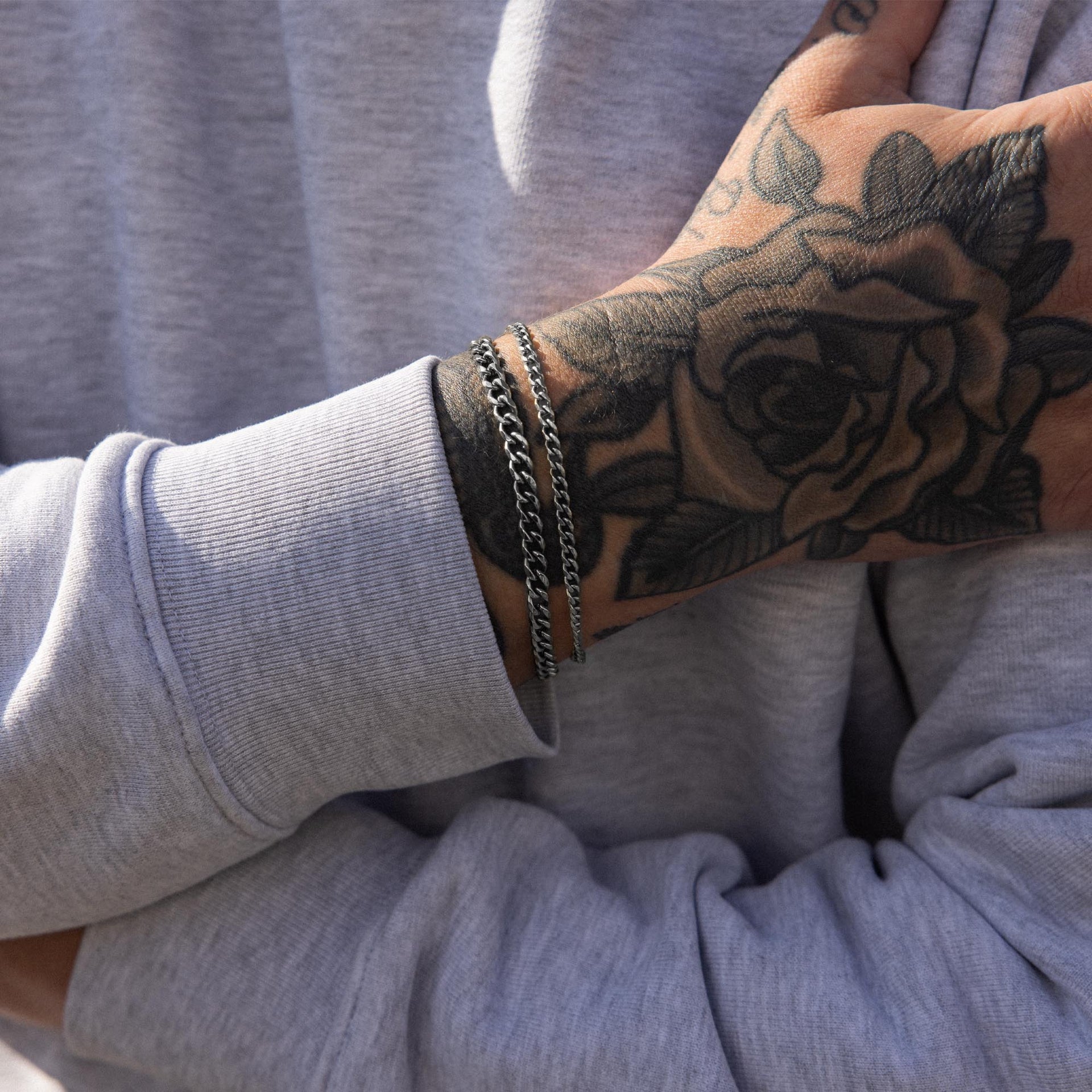 Dreifaches silbernes Armband aus Edelstahl, getragen mit lässigem Sweatshirt, PURELEI Stil.